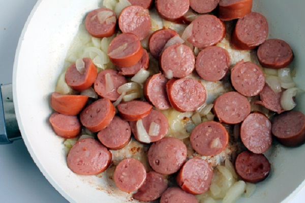 kielbasa cooking with onions in a skillet
